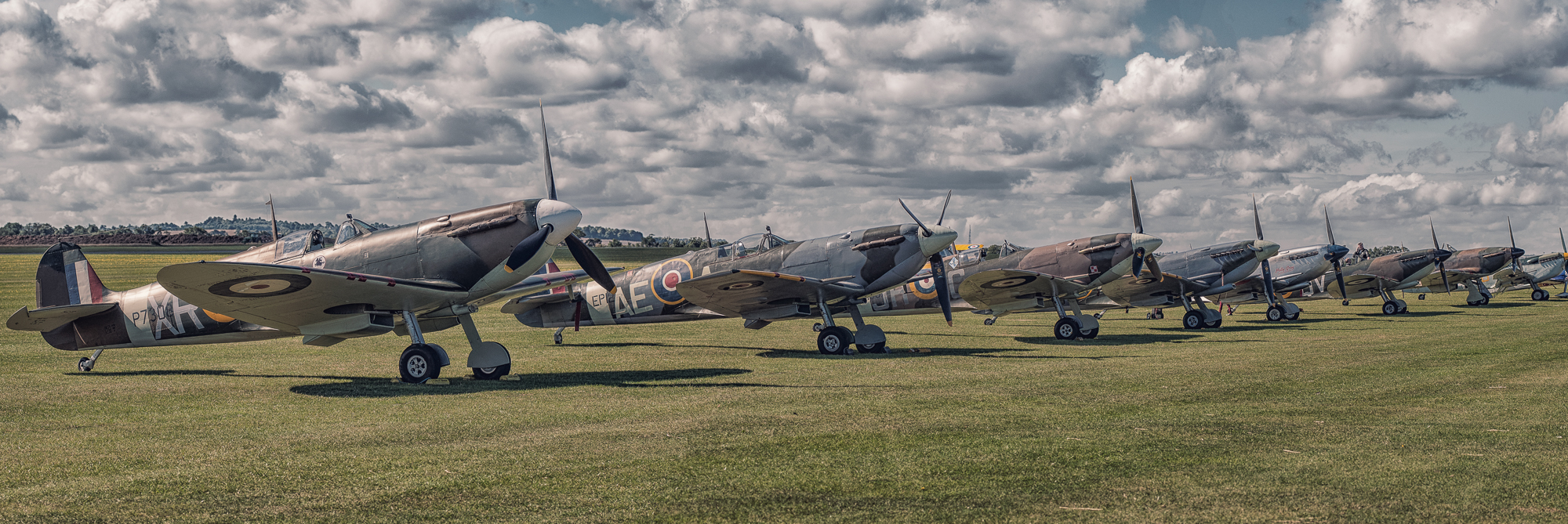 Line-up of six Supermarine Spitfires and a Hawker Hurricane at Duxford