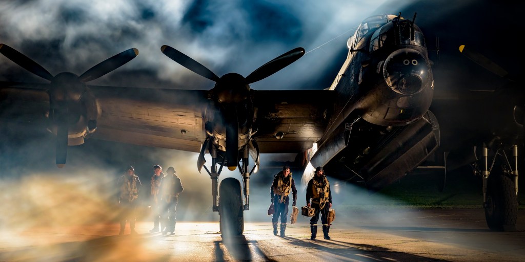Avro Lancaster bomber with aircrew walking out through smoke and dramatic night lighting