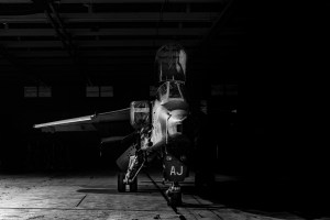 Black and white nose-on view of a SEPECAT Jaguar fighter jet in a hangar