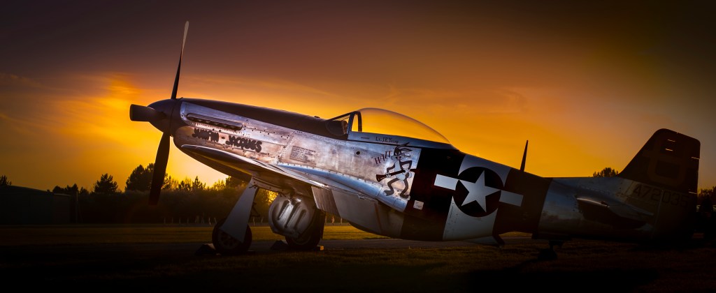 P-51 Mustang fighter 'Jumpin Jacques' silhouetted against a golden sunset