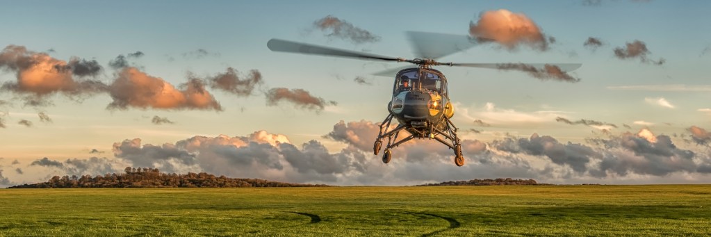 Westland Wasp XT435 helicopter approaching to land over a grass airfield at sunset
