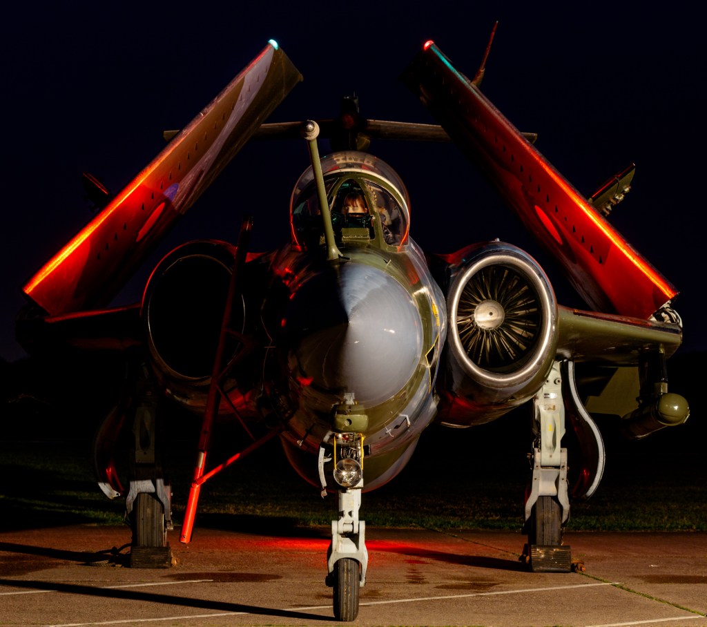 Nose-on view of Blackburn Buccaneer XW544 at night with its wings folded and picked out in red light