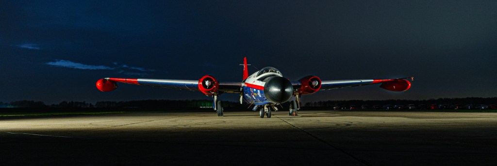 English Electric Canberra WT333 nose-on at night in a red, white and blue scheme with red engine nacelles and wingtip tanks