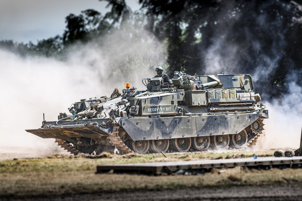 Chieftain armoured repair and recovery vehicle with Recovery Kit stencilled on its side and its dozer blade raised, in the arena at Tankfest, Bovington