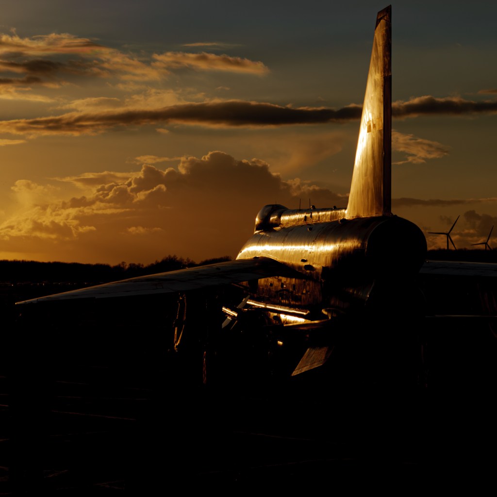 Silhouetted tail fin and rear fuselage of Lightning XR728 against an orange sunset sky