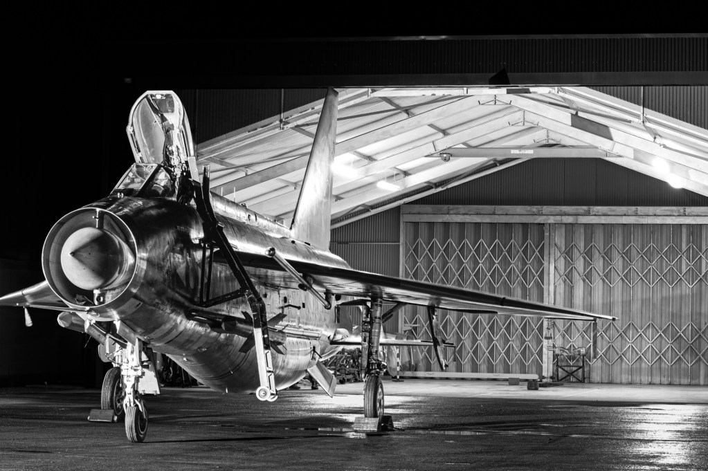 Black and white nose-on view of Lightning XS904 outside the Q Shed at night with its canopy raised