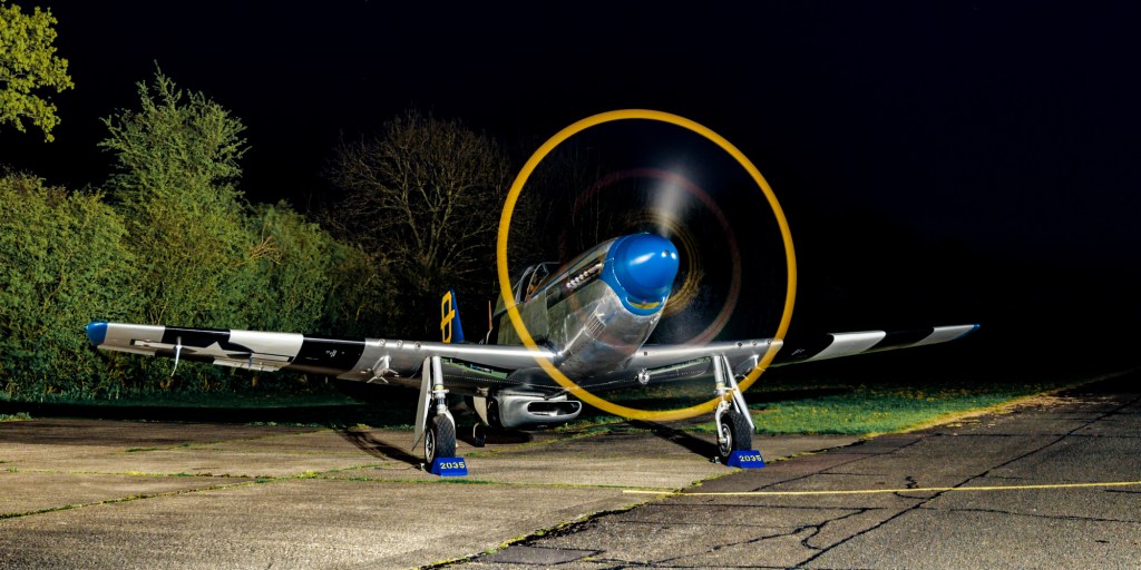 P-51D Mustang Jumpin Jacques on grass at night with a glowing orange propeller ring