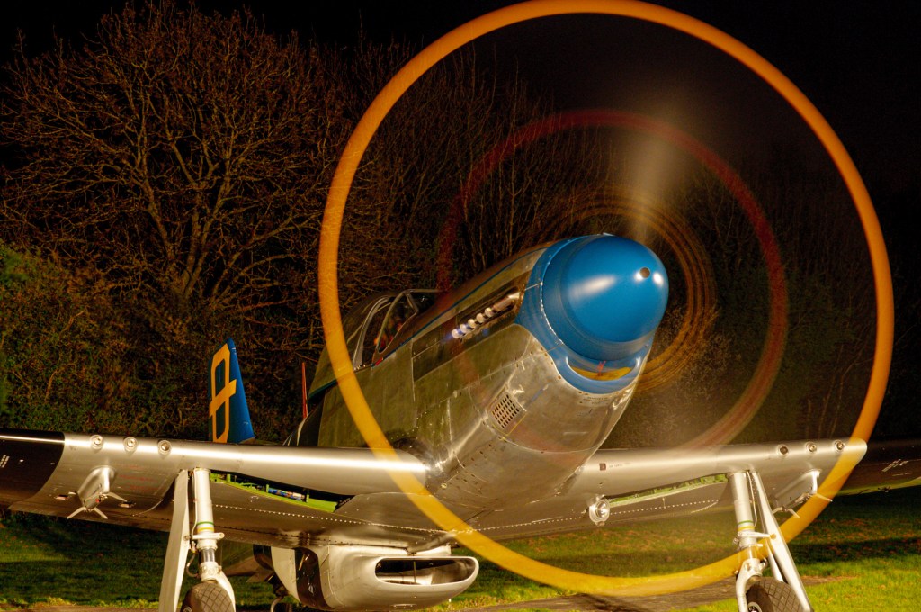 P-51D Mustang Jumpin Jacques at night with a glowing orange ring of light from its spinning propeller